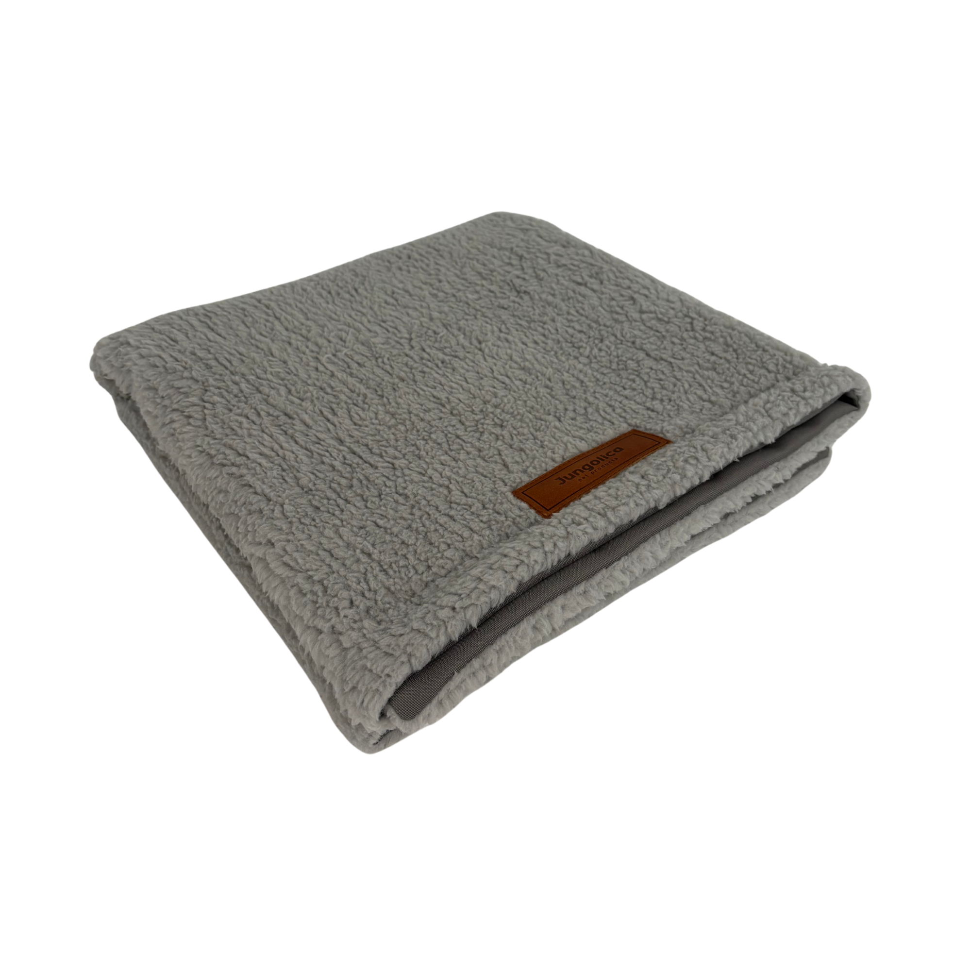 Folded light gray fleece blanket with soft texture and leather tag on a white background
