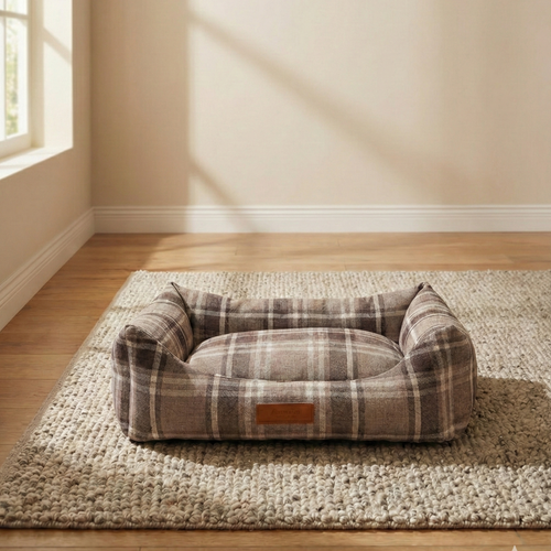 Plaid rectangular dog bed on textured rug in sunlit room with hardwood floors