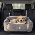 Golden retriever puppy in a gray pet car seat with colorful safety straps on black leather seats