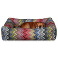 Small dog sleeping on a colorful zigzag-patterned pet bed