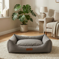 Gray fabric pet bed on a beige rug in a modern cozy living room with neutral decor.