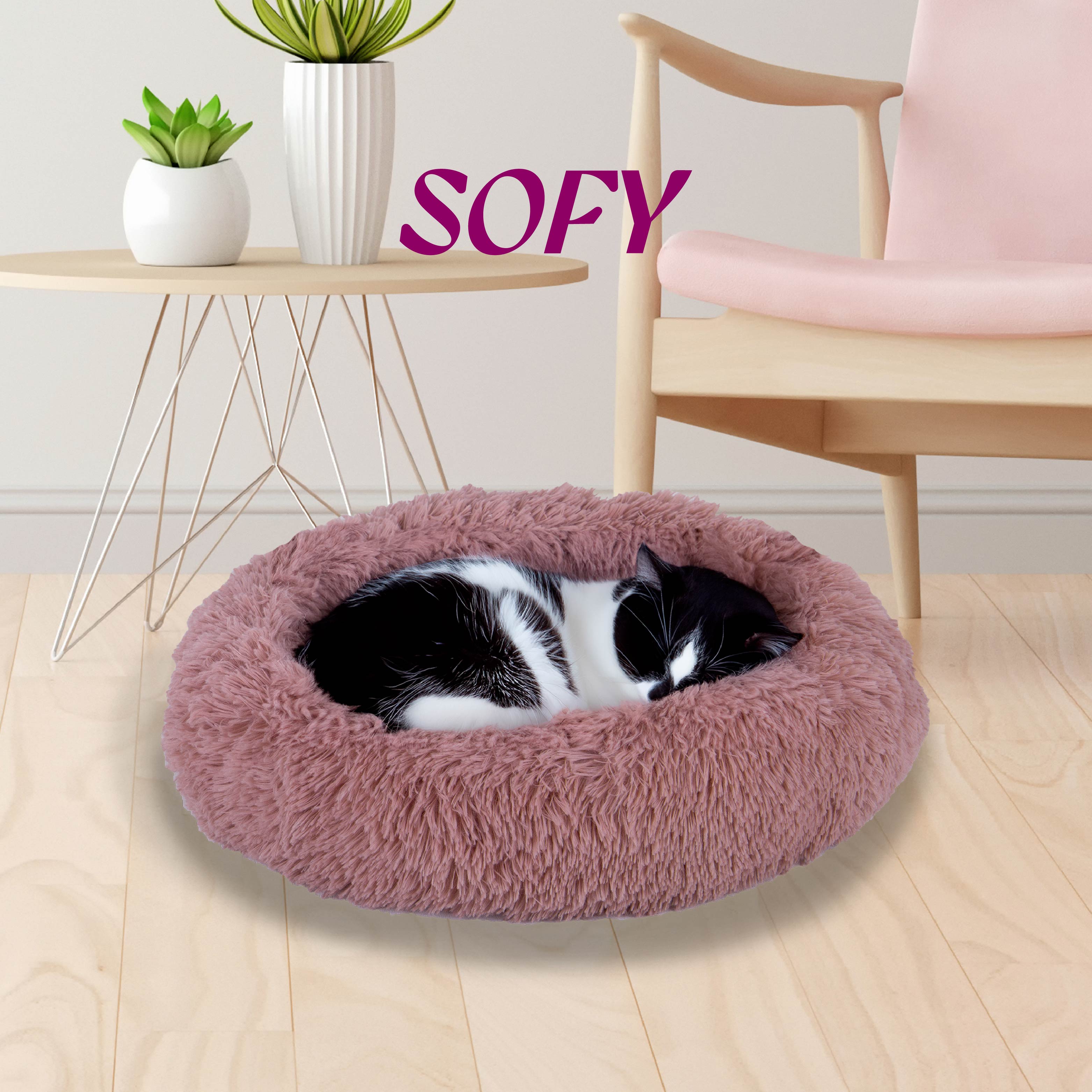 Black and white cat sleeping in a pink fluffy pet bed in a modern living room